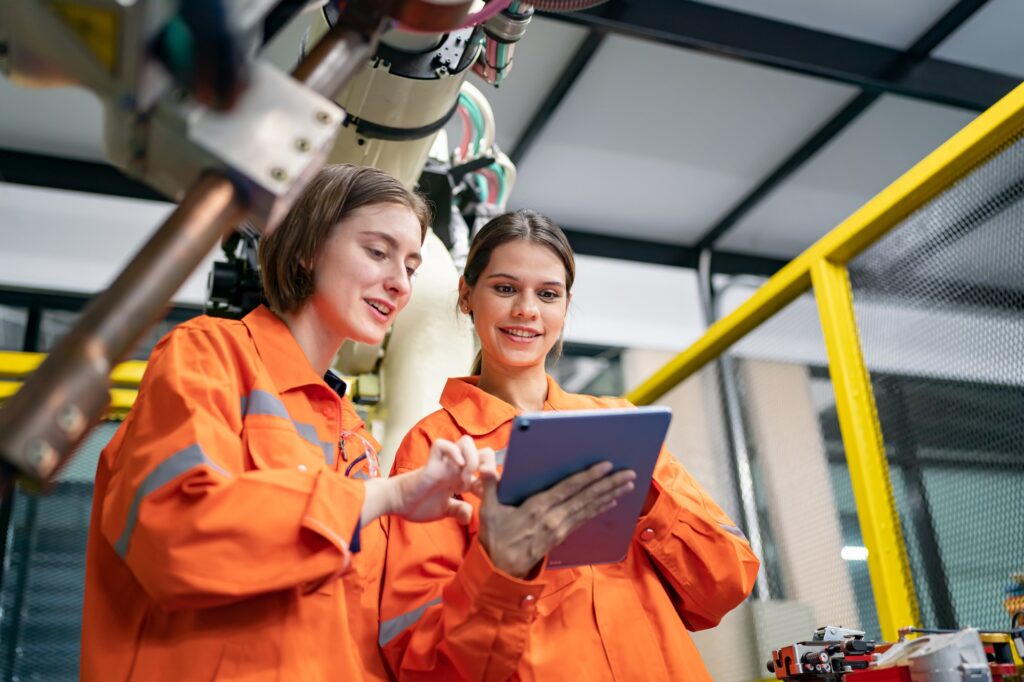 Female Engineer check and control automation robot arms machine in factory. robotics manufacturing.